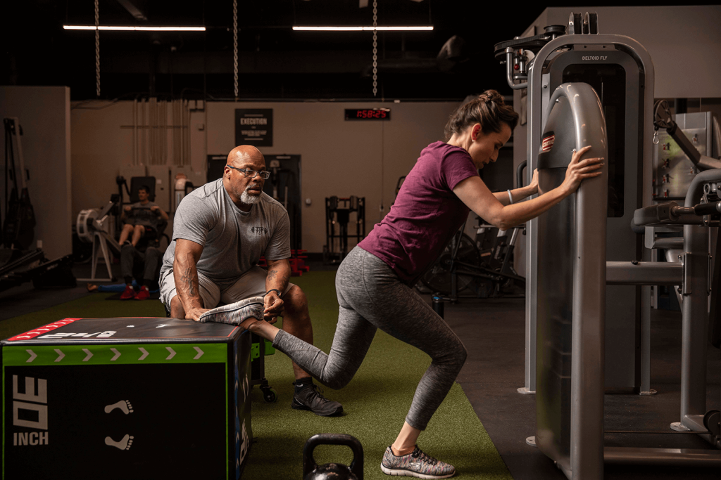 Personal trainer supervising woman working out in a gym